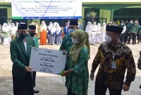 Ketua Umum Pengurus Besar Mathla'ul Anwar (PBMA) KH Embay Mulya Syarief (kiri) menyerahkan santunan BPJS Ketenagakerjaan kepada keluarga almarhum Dr. Akhsan Sukroni di Perguruan Pusat Mathla'ul Anwar di Menes, Pandeglang Banten pada 17 Agustus 2021 (Foto: Istimewa)